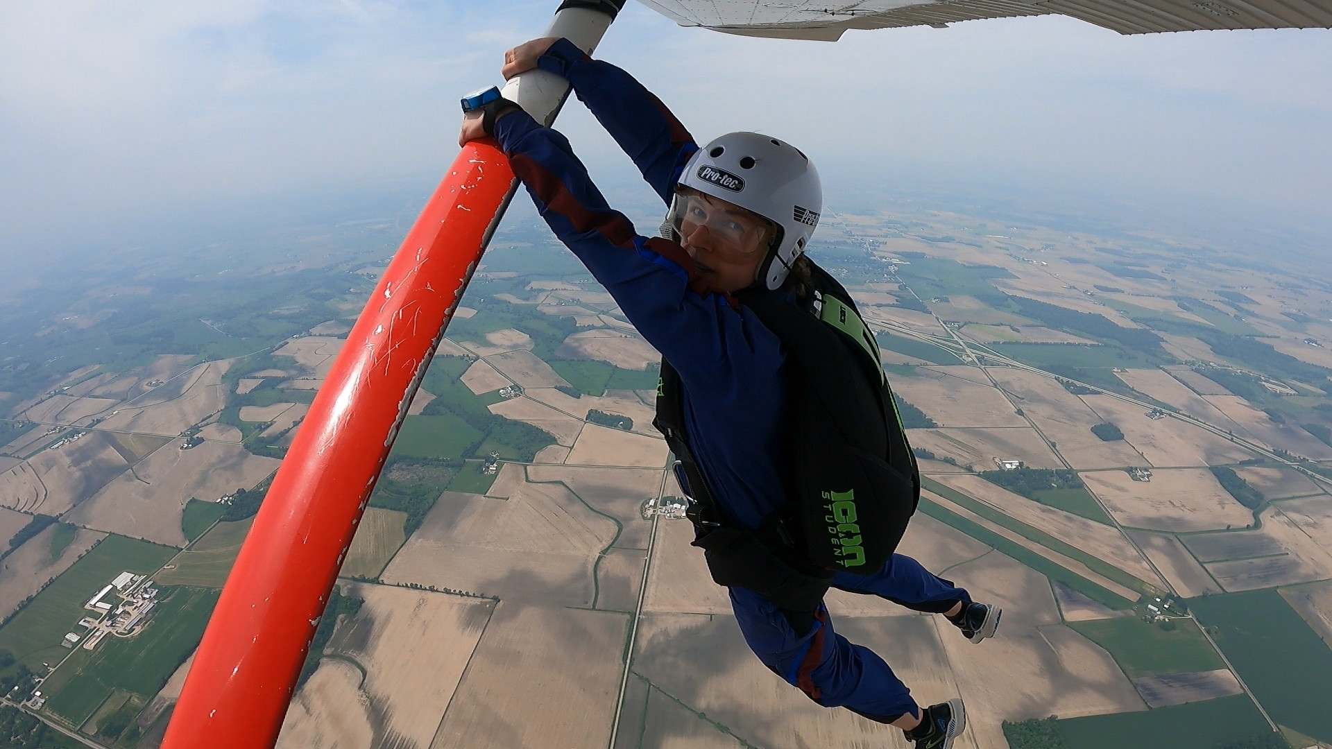 Skydiver hangs off the strut of a C182, approximately 5,000 feet AGL